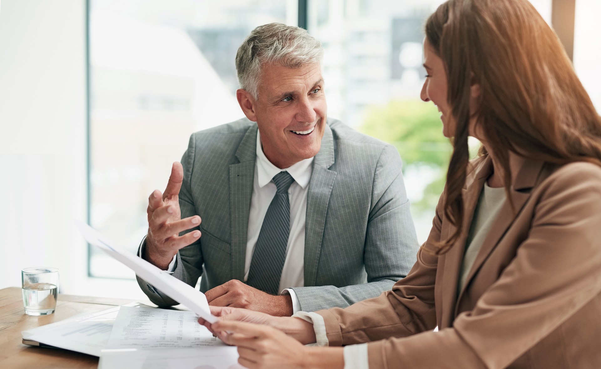 Réunion, homme et femme d’affaires avec des documents pour des conseils, une planification et une conversation à table. Office, contrat b2b et consultation d’une fille avec un conseiller financier pour une transaction commerciale, un soutien et une d